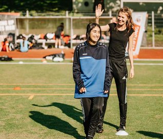 Trainerin und Mädchen lachend auf dem Fußballfeld