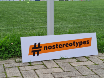 Orangener #nostereotype-Banner an Pfosten angelehnt