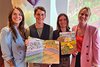 Die Gründerinnen von Ulila und zwei Teammitglieder von Klischeefrei im Sport halten das Wimmelbuch zum Thema Sport hoch.