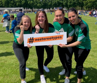 Drei Spielerinnen halten das orangene #nostereotypes-Banner